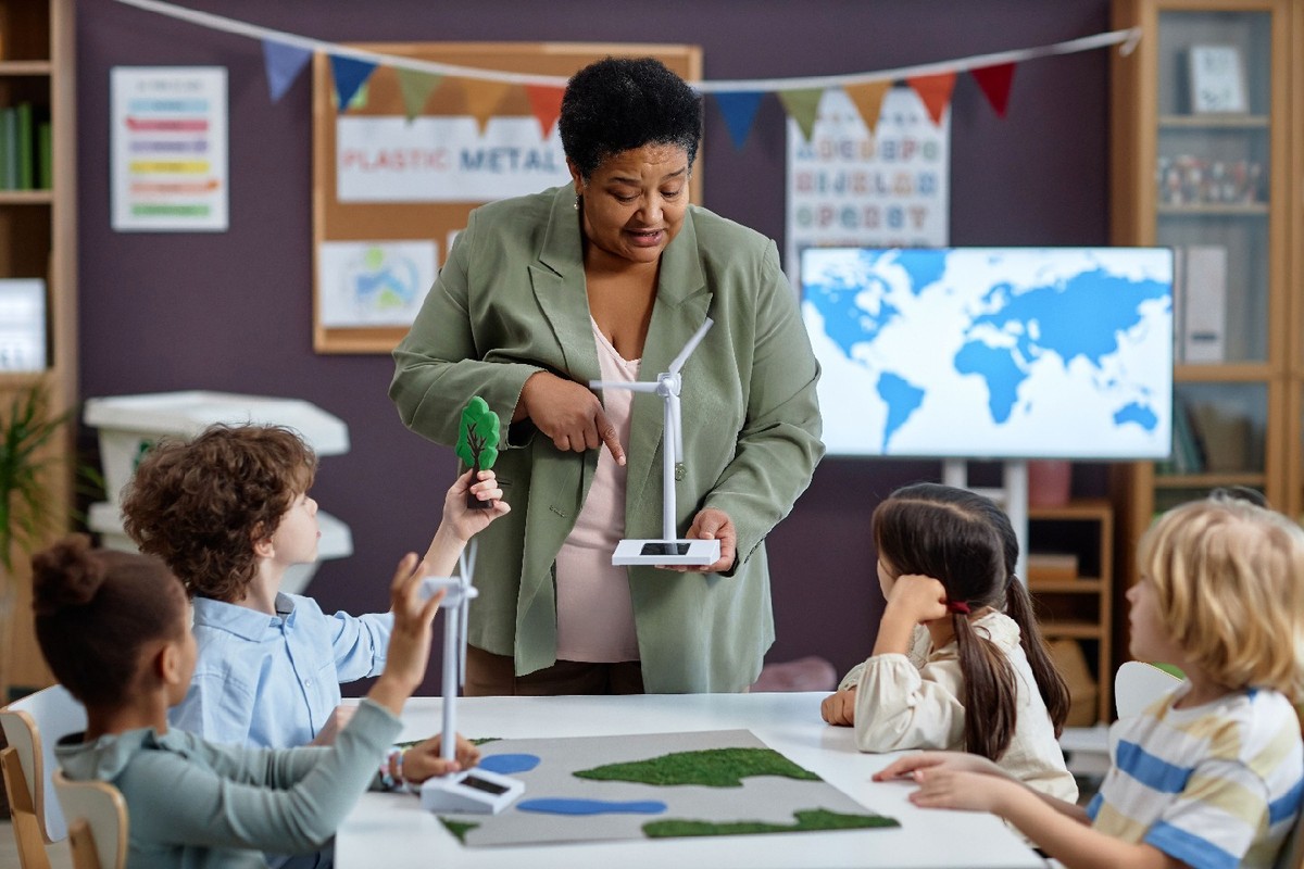 A teacher holds a model turbine in front of students seated in a classroom.